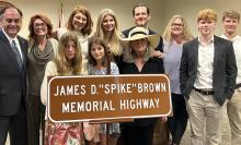 The Brown family and friends stand next to the sign that will go up along I-22 in honor of James “Spike” Brown. Left to right, top row: State Representative Tracey Estes, Susannah Brown, Alexandra Leigh M.D., Beatrix Brown, Nathan Brown M.D./D.M.D., Meredith Brown and Kenneth Mays III (Tripp). Bottom row: Myrina (Minnow) Brown, Alexandra (Honey) Brown, Cynthia Brown and Dylan Mays.