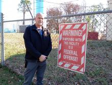 Bear Creek Mayor Rob Taylor stands at the break-in site, next to a sign warning any tampering with the facility is a federal offense.